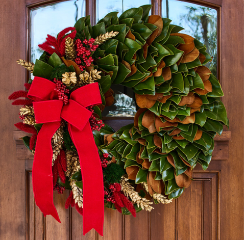 Magnolia Christmas wreath with red bow on a wooden door