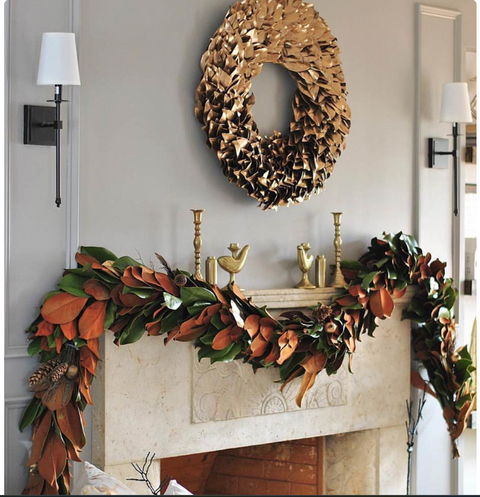 Decorative wreath and garland on a fireplace mantel with gold accents.