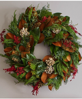 Decorative wreath with greenery, red berries, and pinecones on a plain background