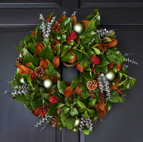 Magnolia wreath with fresh greens, pine cones and red berries.
