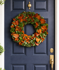 real magnolia wreath hanging on navy door